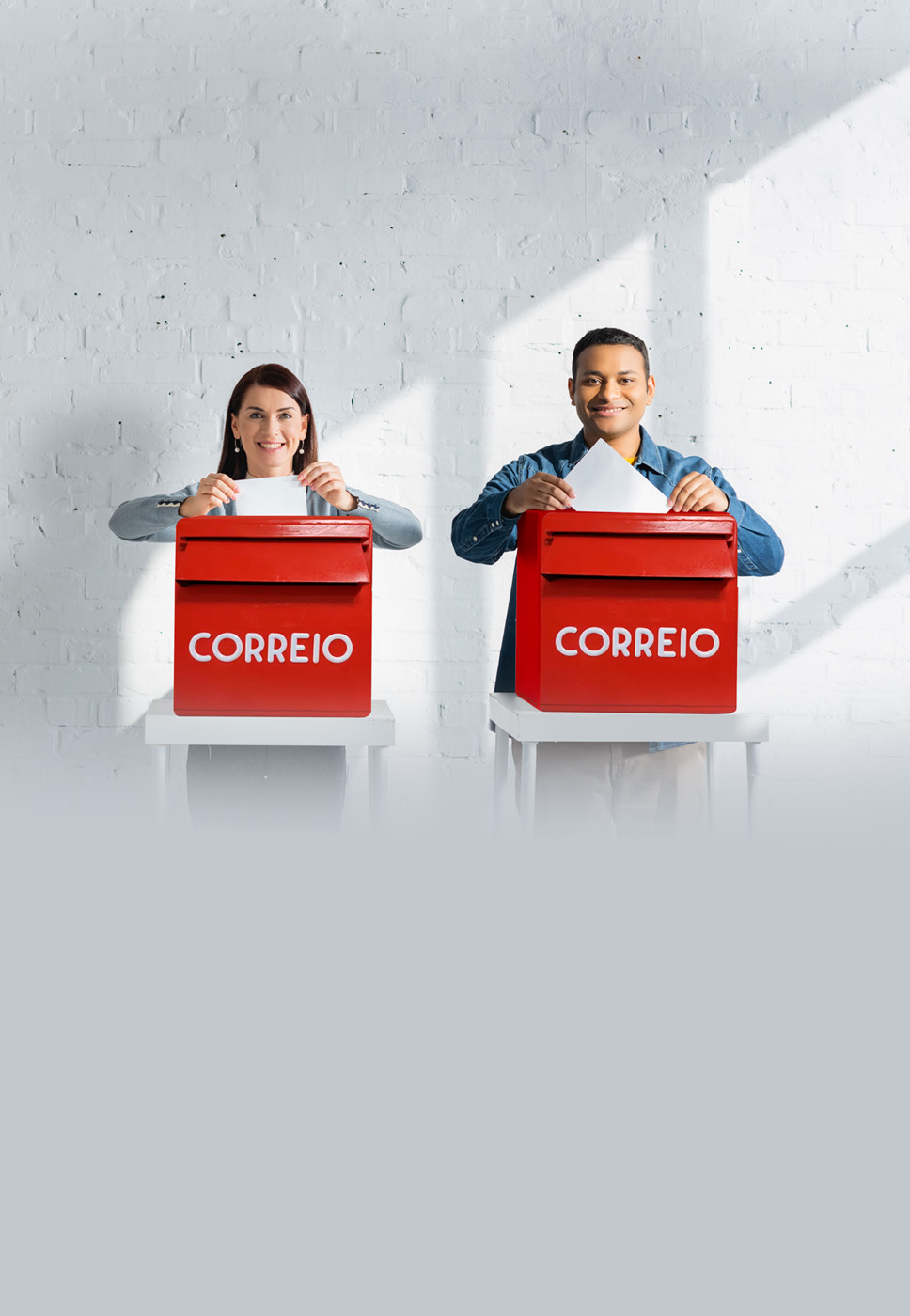 dois indivíduos a colocar um boletim de voto no marco de correio