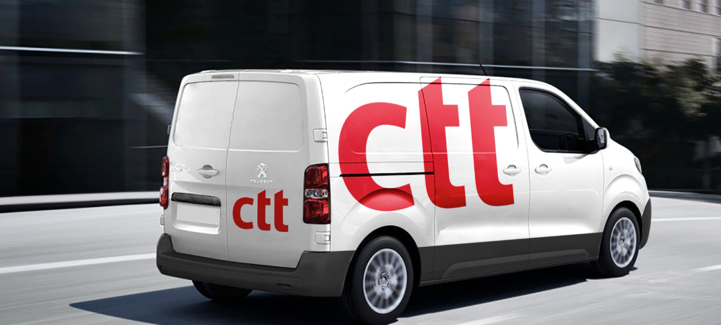 Carrinha branca dos CTT, em movimento numa estrada urbana.