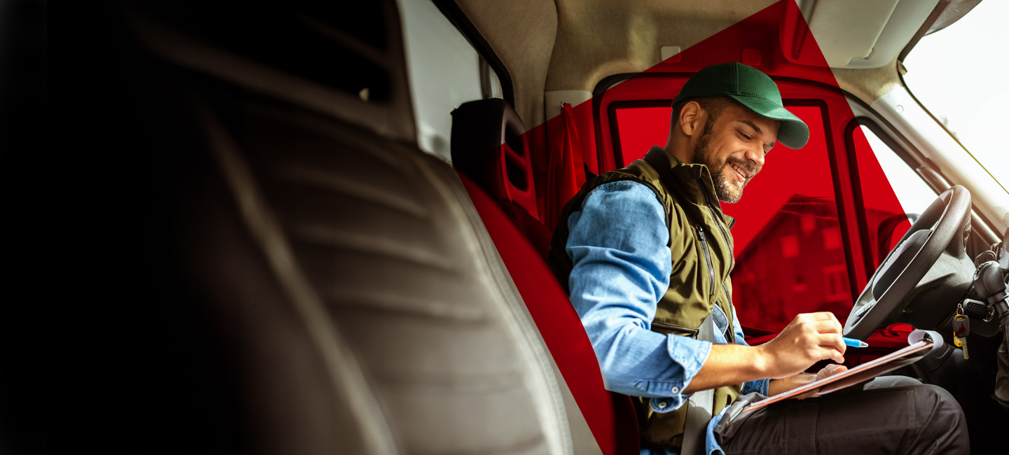 Senhor sentado numa carrinha a tirar anotações.
