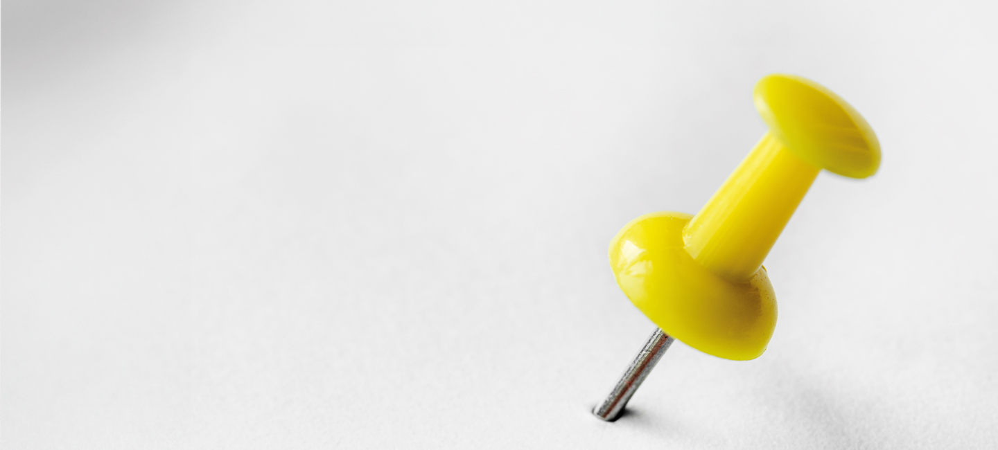 Alfinete de quadros espetado numa folha branca