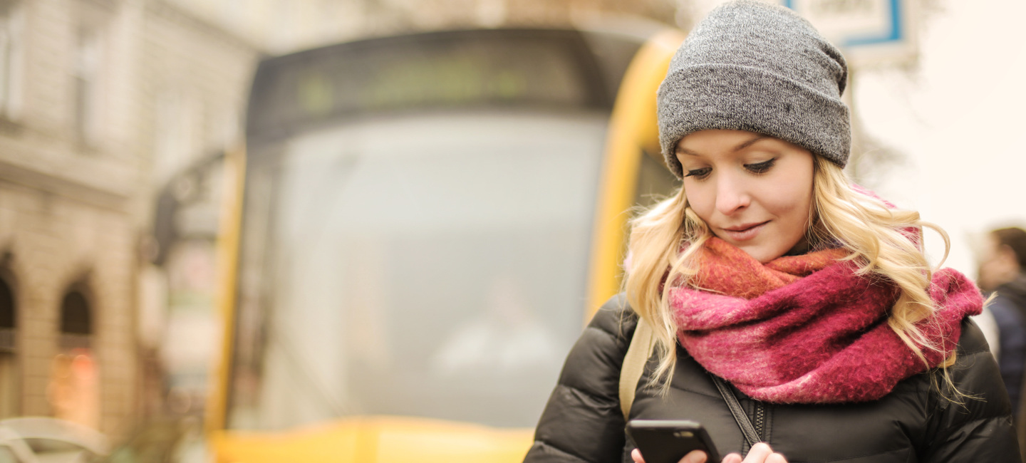 Senhora pesquisa no seu telemóvel onde pode fazer o carregamento do seu passe.