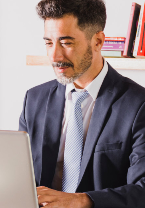 Senhor que está sentado a mexer o computador.