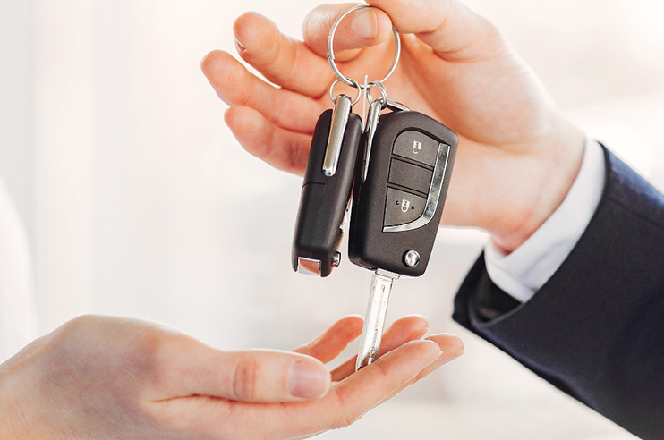 Senhor a entregar a chave de um carro a outra pessoa.